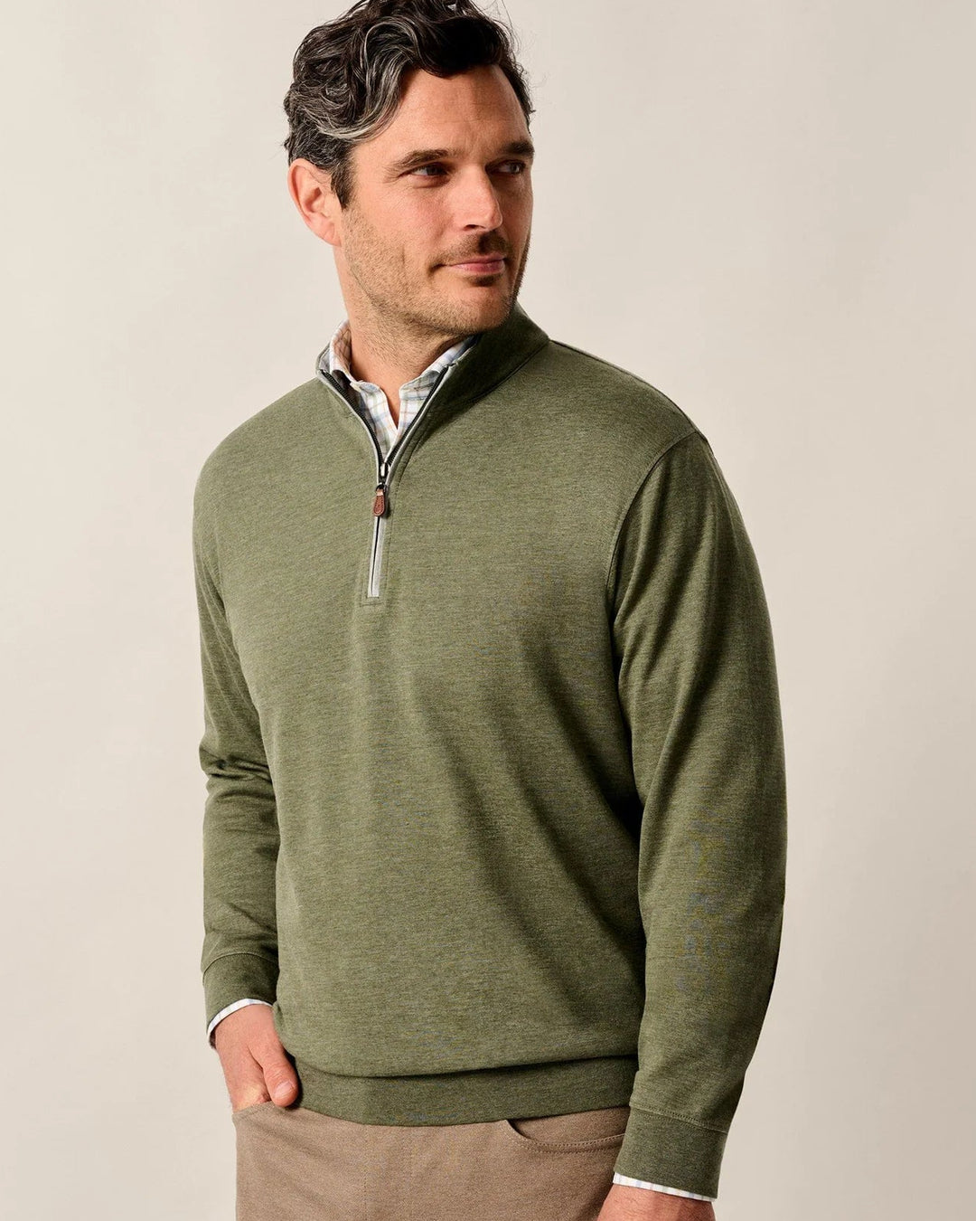 Man wearing a green quarter-zip sweater against a beige background